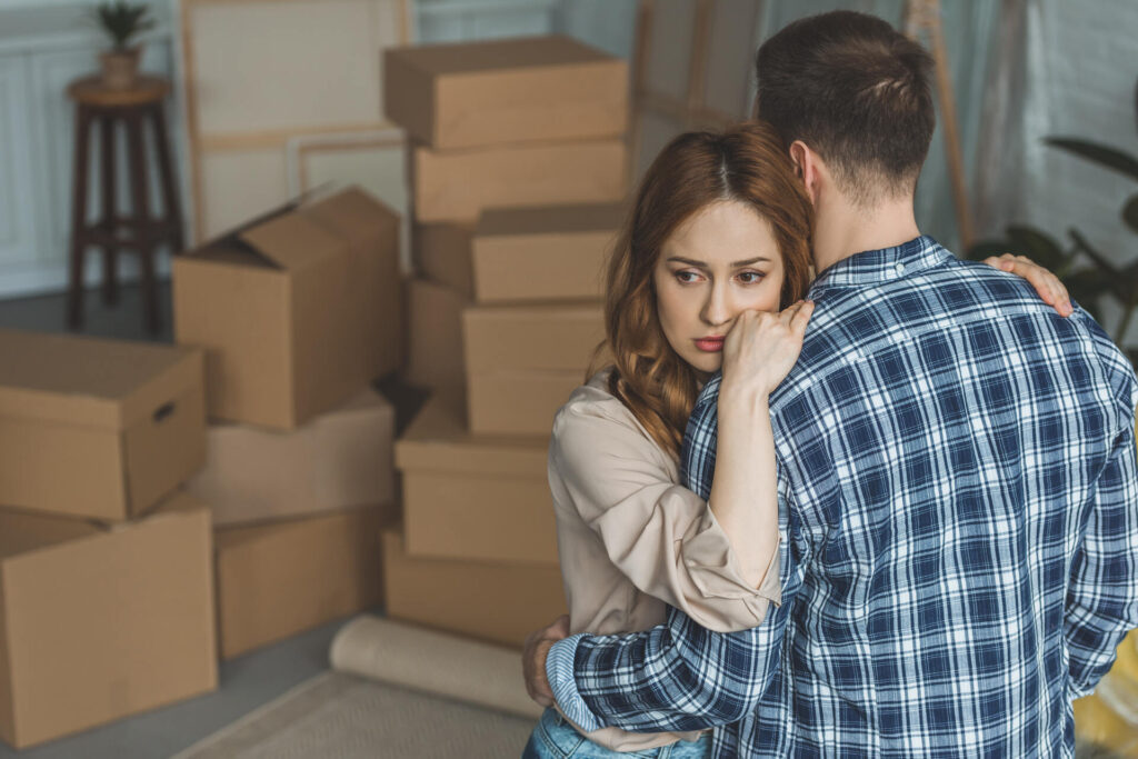 couple hugging at new apartment full of cardboard boxes, moving home