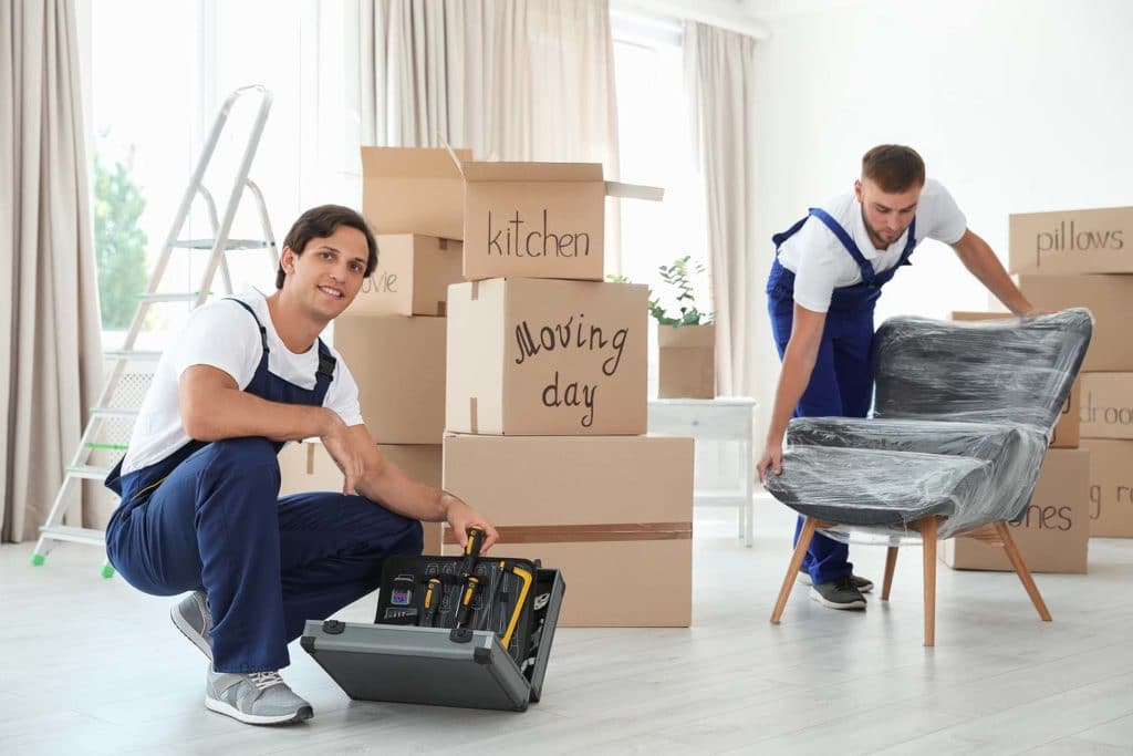 Two state-to-state movers surrounded by boxes, one of them lifting a chair