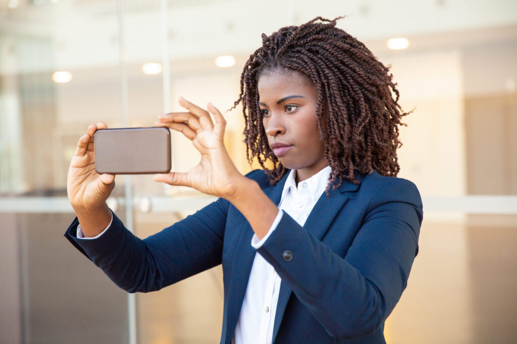Focused female professional taking picture on cellphone before moving