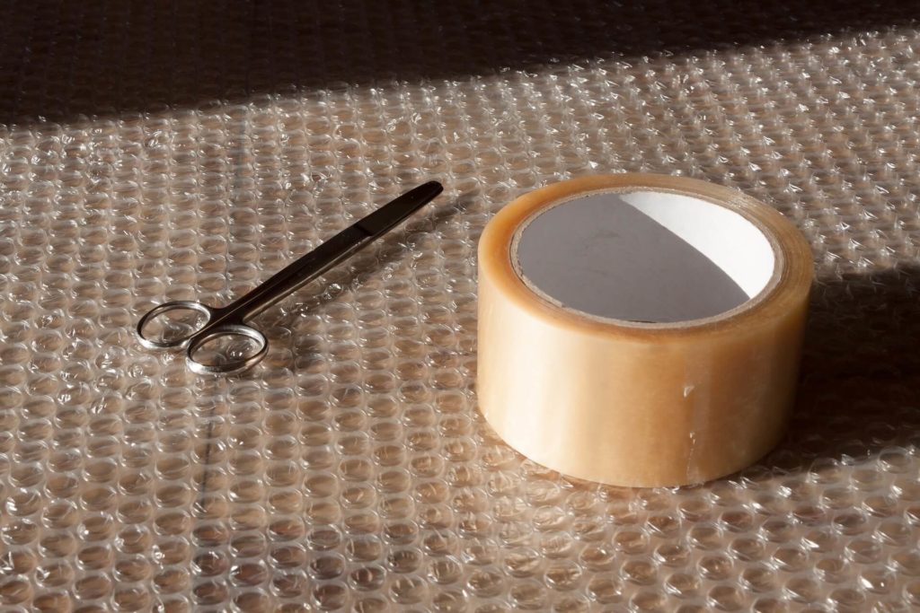 A bubble wrap, scissors, and tape on a table