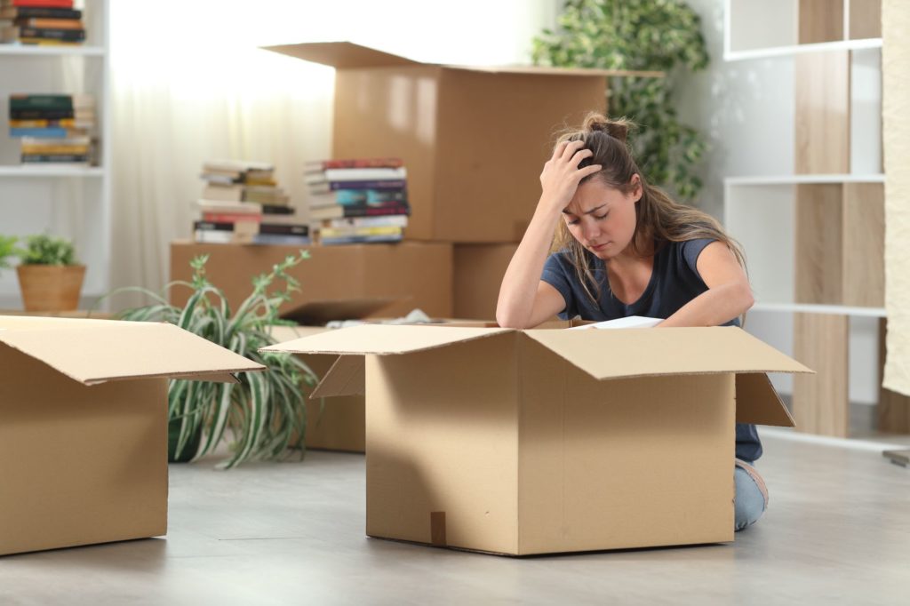 a worried woman sitting on the floor, unpacking after a long-distance move