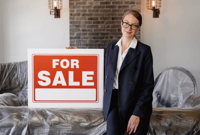 woman next to a for sale sign