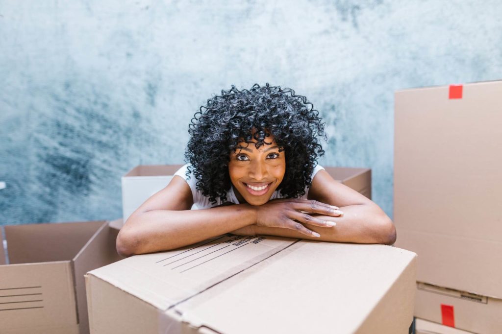 Smiling woman leaning on a box before moving interstate