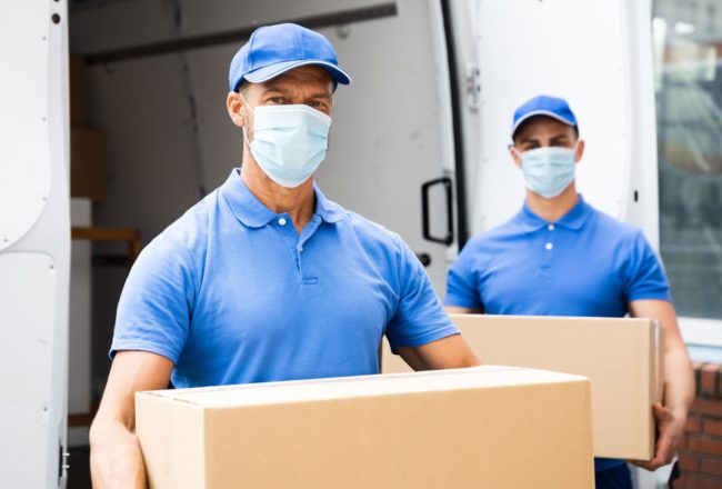 movers with masks holding boxes