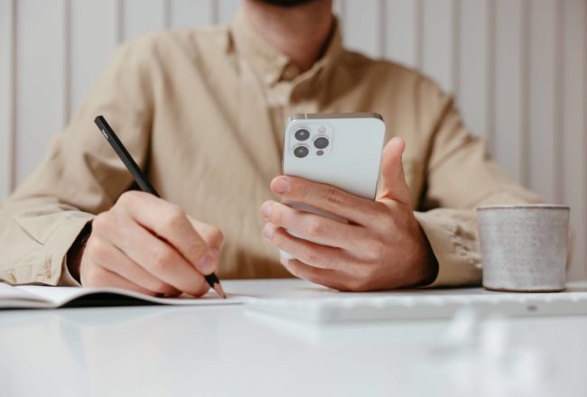 man holding a phone and making notes
