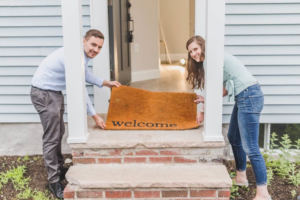 couple holding a welcome mat after a long - distance moving