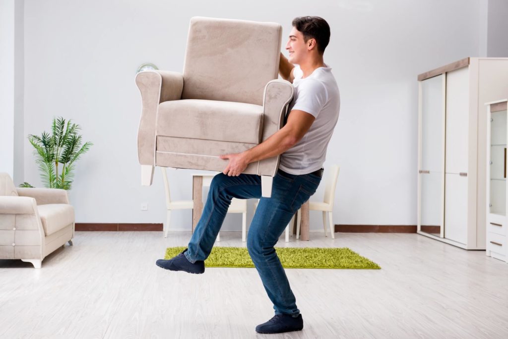 Guy lifting an armchair alone instead of hiring professional state to state movers