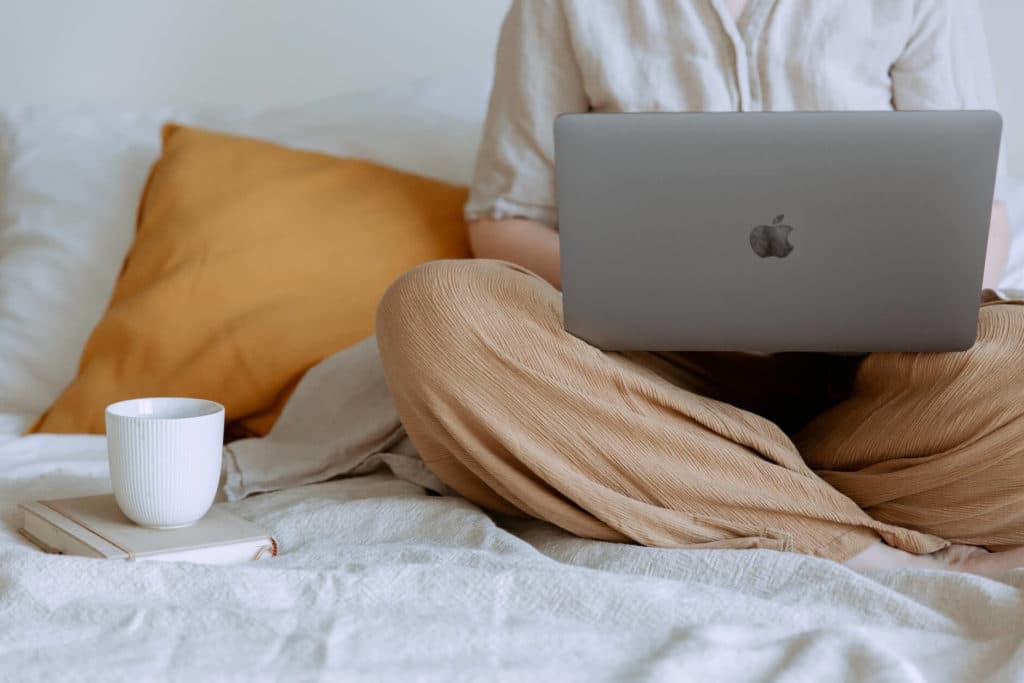 A woman sitting on the bed and holding a laptop before moving state to state
