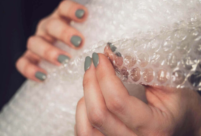 Woman holding a roll of bubble wrap before moving interstate