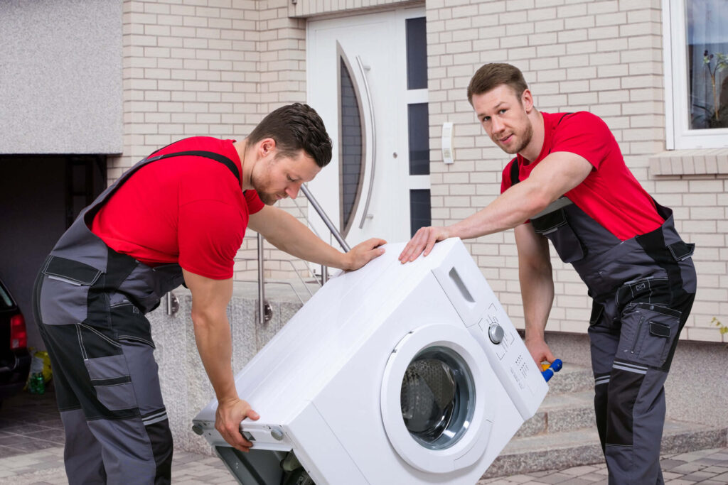 State-to-state movers maneuvering a washing machine with a dolly