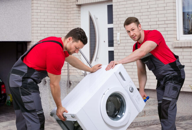 State-to-state movers maneuvering a washing machine with a dolly