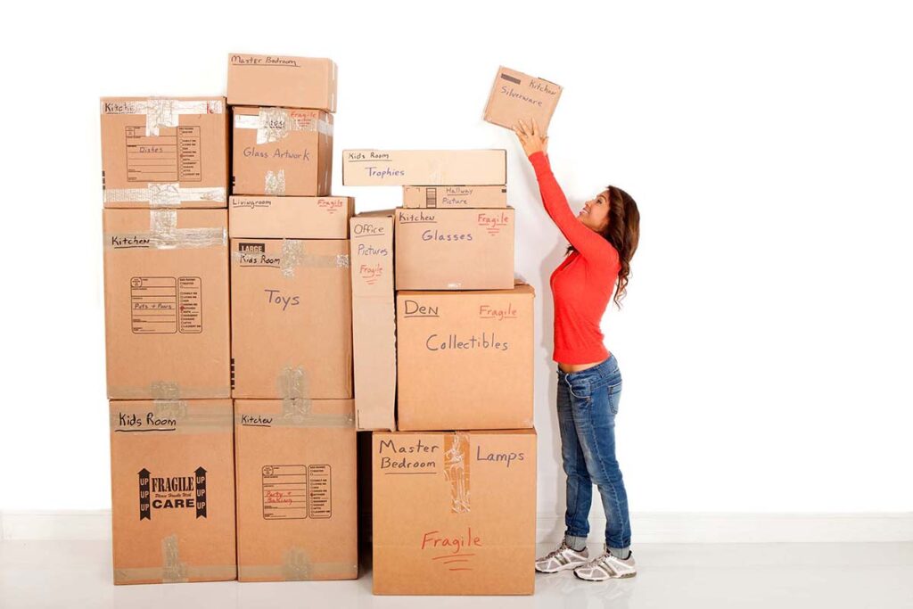 A woman putting a labeled box on a huge stack of boxes