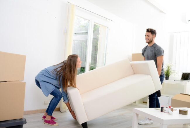 A man and a woman lifting a white couch