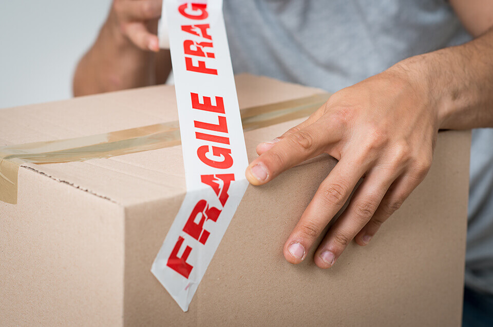 A person putting a fragile label on a box
