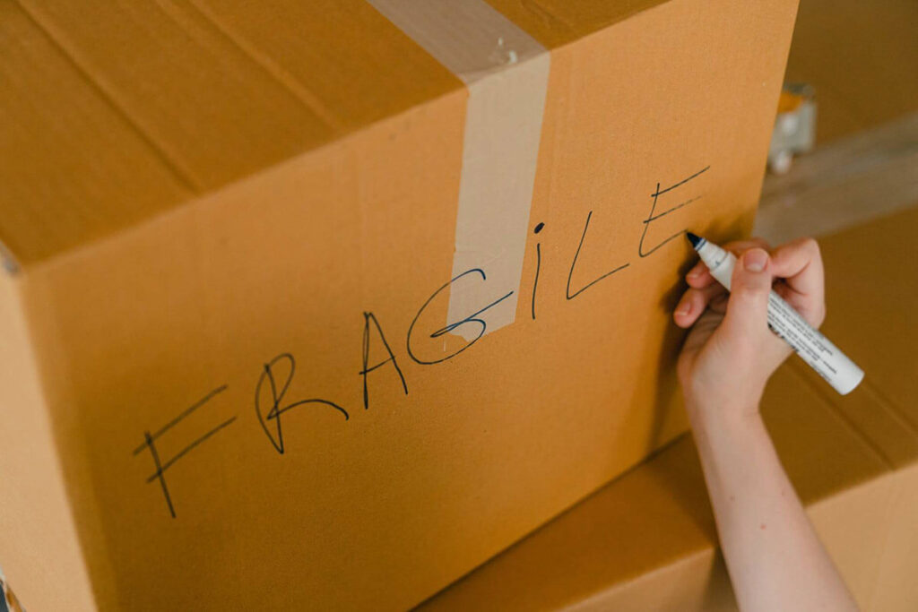 A person writing fragile on a box