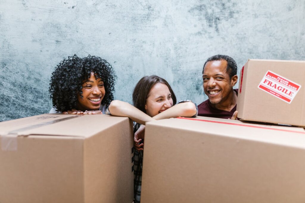 Three friends having fun while unpacking boxes